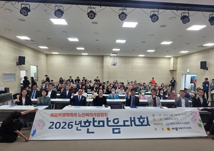 ‘2026년 한마음대회’ 현수막 뒤로 참석한 종사자와 어르신, 내빈들이 객석에 모여 기념사진을 찍고 있다