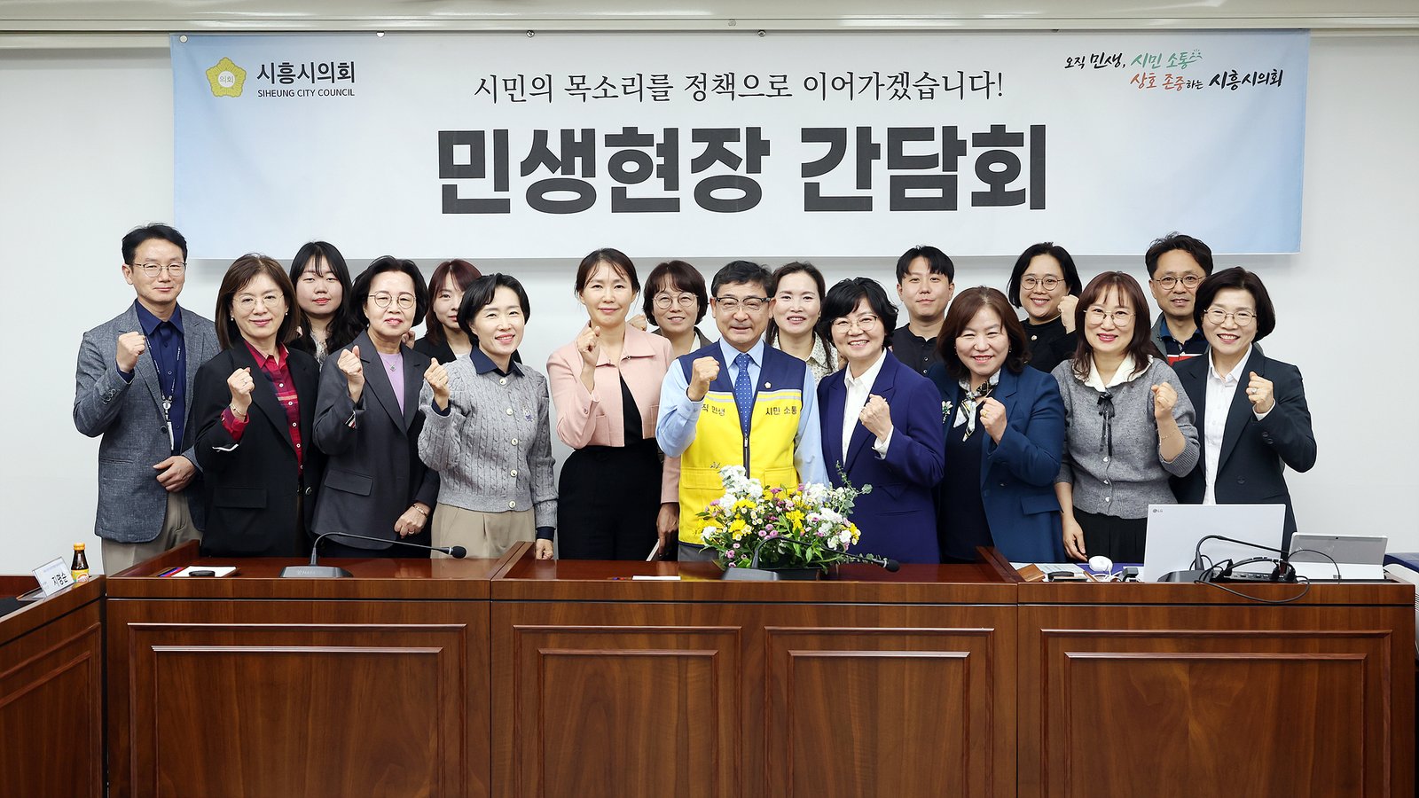 시흥시의회 의회운영회의실 ‘민생현장 간담회’ 현수막 앞에서 김선옥 의장과 노인장기요양기관 관계자들이 주먹을 쥐어 보이며 단체 사진을 찍고 있다